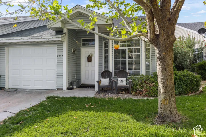 Light gray siding exterior with a white paneled garage door, a front entry with a transom window, and a bay window featuring multiple panes