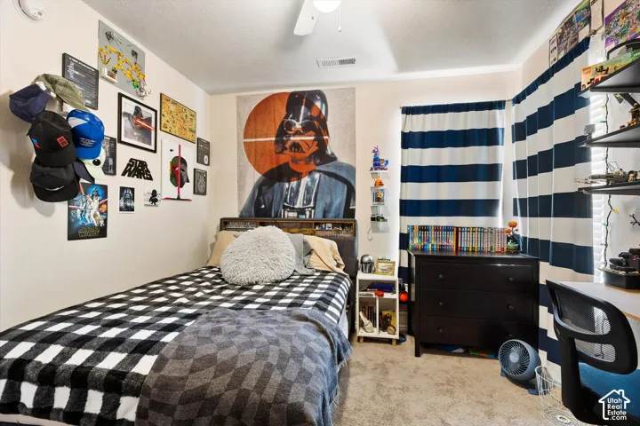 Carpeted room with a ceiling fan, window with horizontal striped curtains, and a built-in wall shelf unit