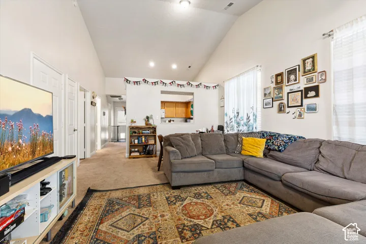 Vaulted ceiling, recessed lighting, carpet flooring, and a kitchen pass-through