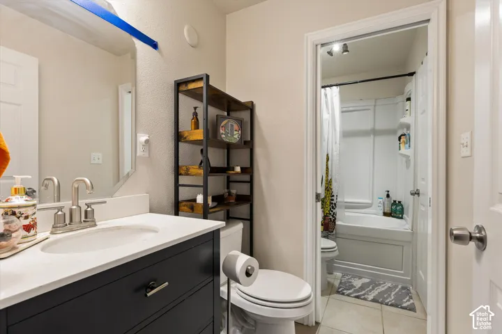Bathroom featuring a single vanity with a white countertop and dark cabinetry, a wall-mounted mirror, and a tub/shower combination with a white surround