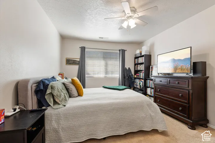 Recessed window with blinds and dark curtains, neutral wall tones, textured carpeting, and a ceiling fan with light fixture