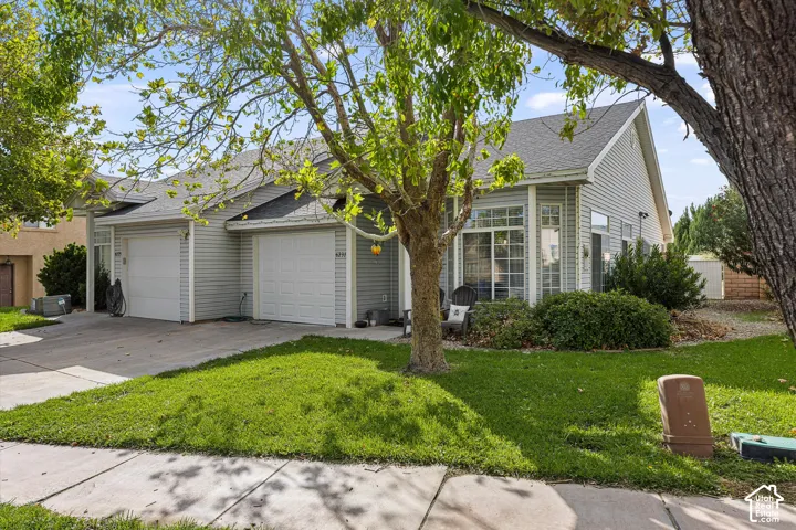 Light-colored siding, dual garage doors, front lawn, and mature trees