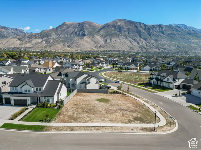 Vacant land parcel with mountain backdrop, surrounded by residential development, and featuring paved street access