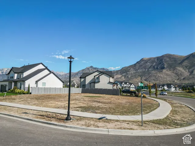 Expansive lot with mountainous backdrop, featuring an existing street lamp and curved sidewalk