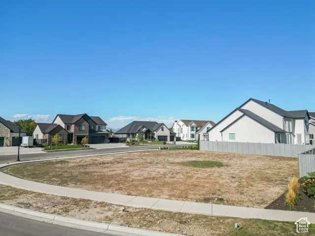 Expansive open lot with sidewalk frontage, surrounded by modern residential architecture