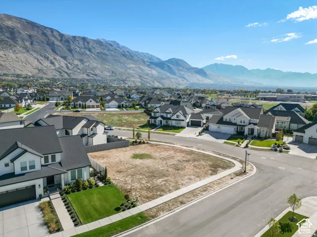 Expansive lot with mountain backdrop, surrounded by established residences, featuring a clear building area and street-level access