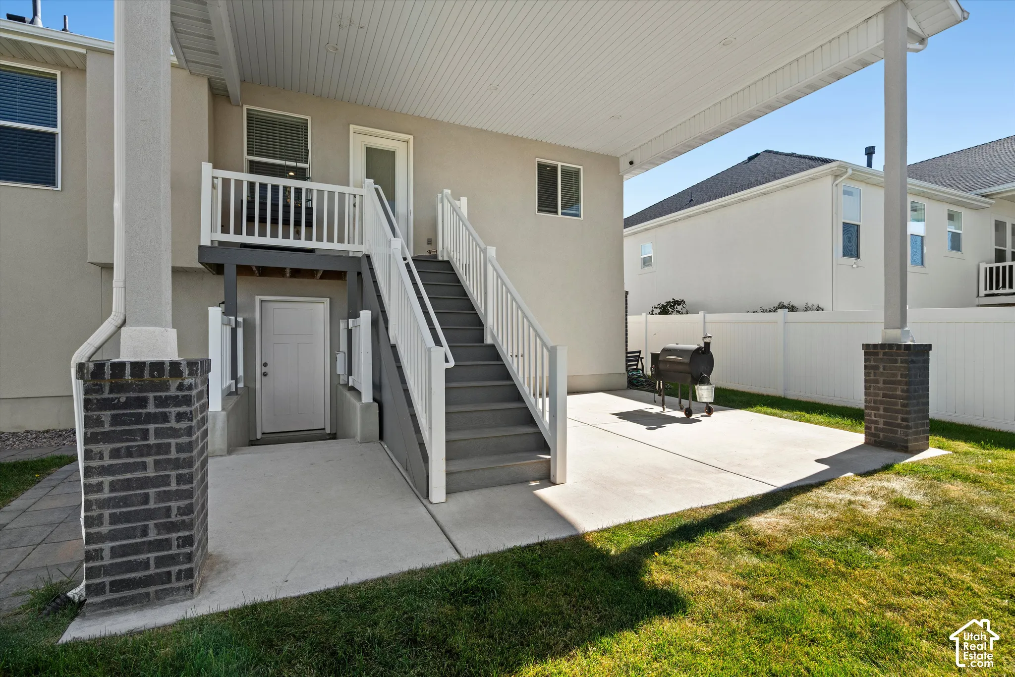 Covered patio with concrete flooring, supported by brick-clad columns