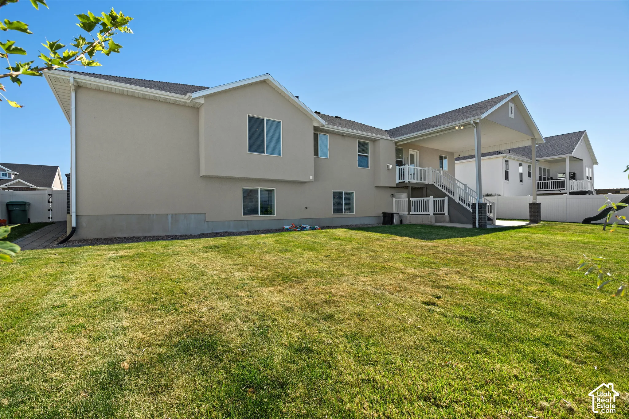 Expansive backyard featuring a covered patio, upper-level deck, and mature lawn
