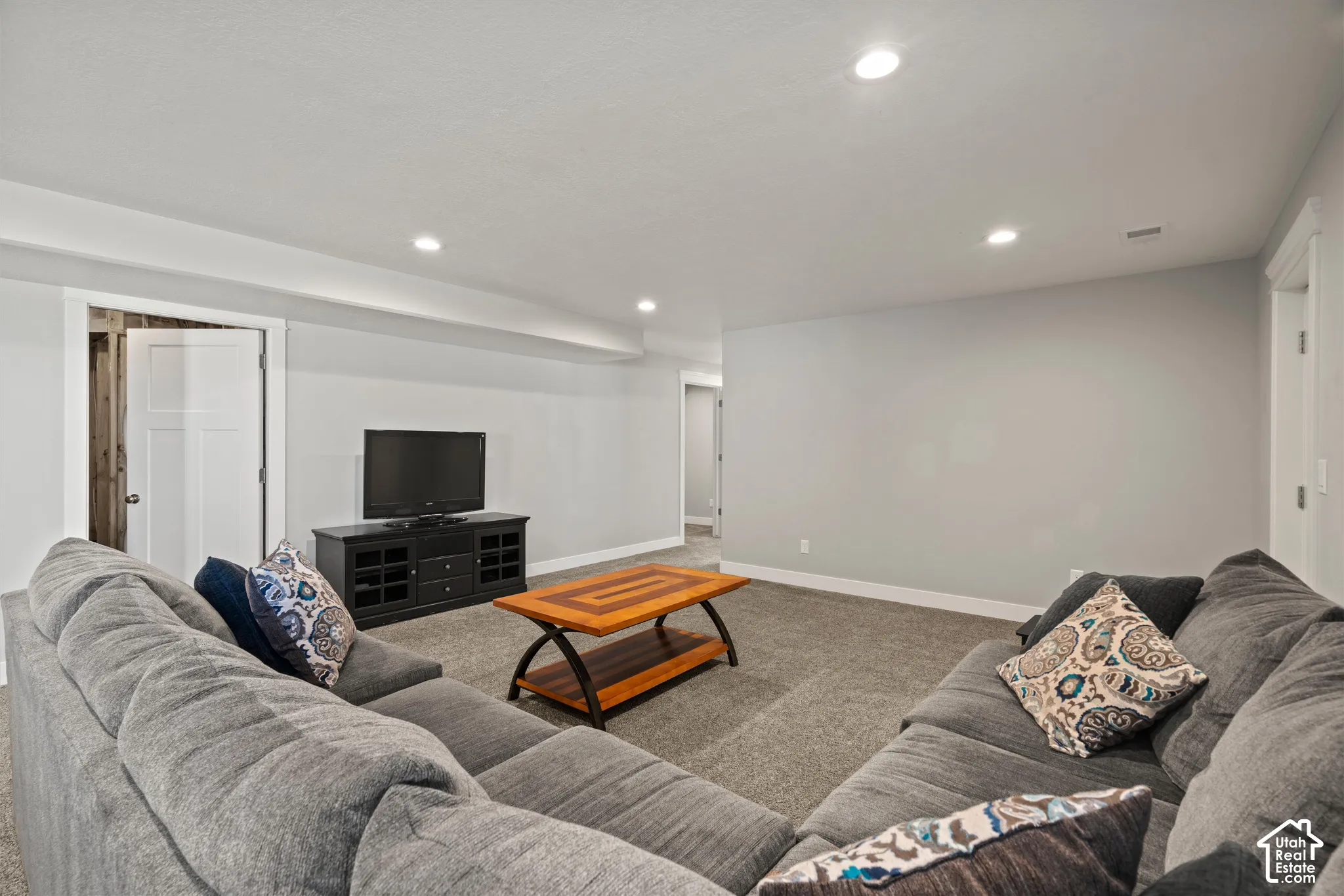 Recessed lighting illuminates the carpeted floor and light gray walls