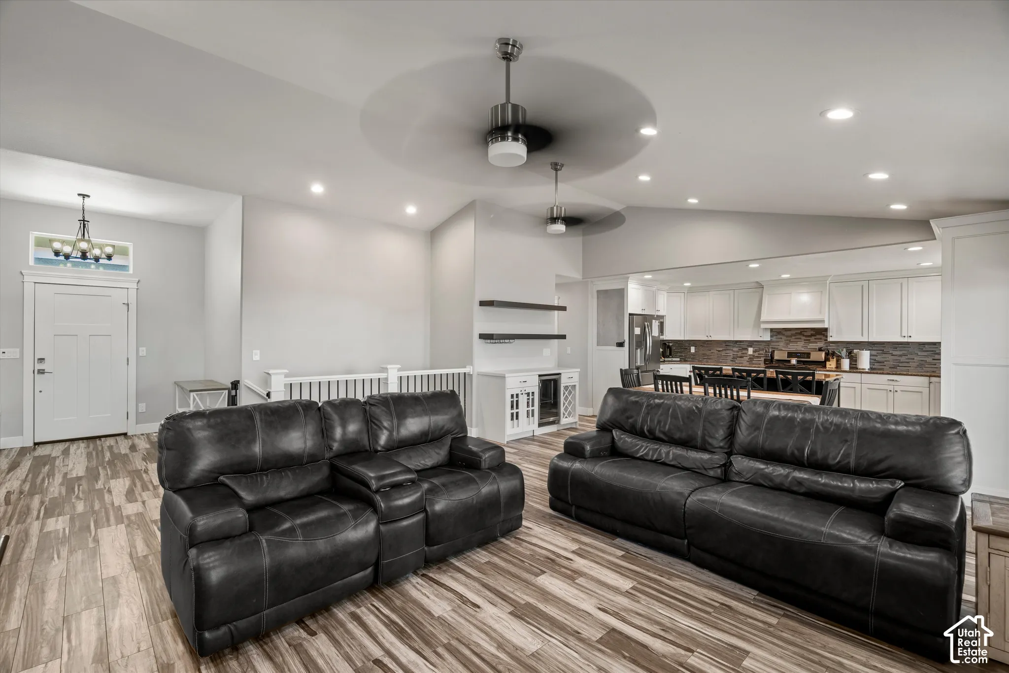 Vaulted ceilings with recessed lighting, wood-finish flooring, white wood railings, built-in shelving, and white cabinetry