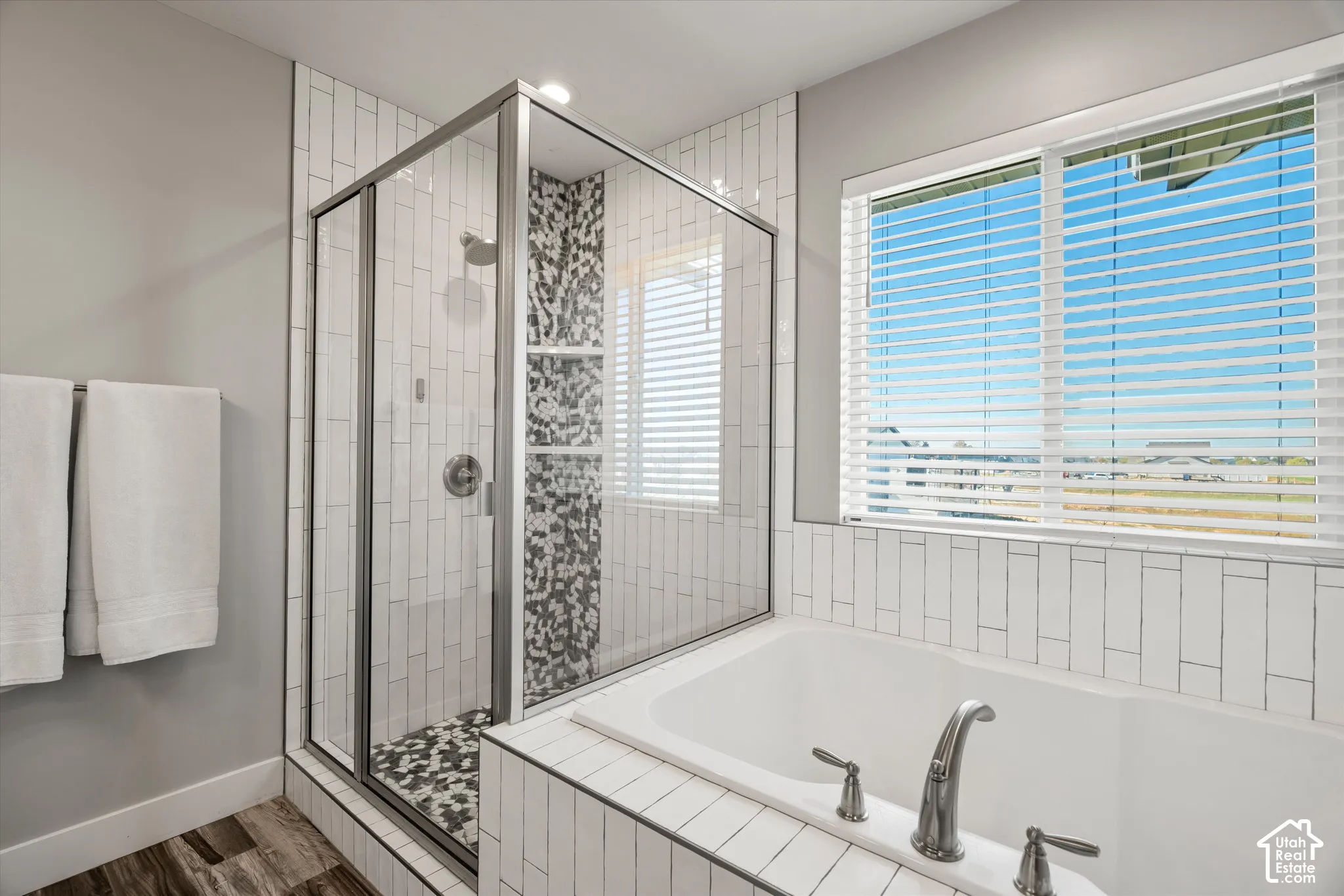 Soaking tub and tiled separate shower in  primary bathroom. Beautiful mosaic tiles