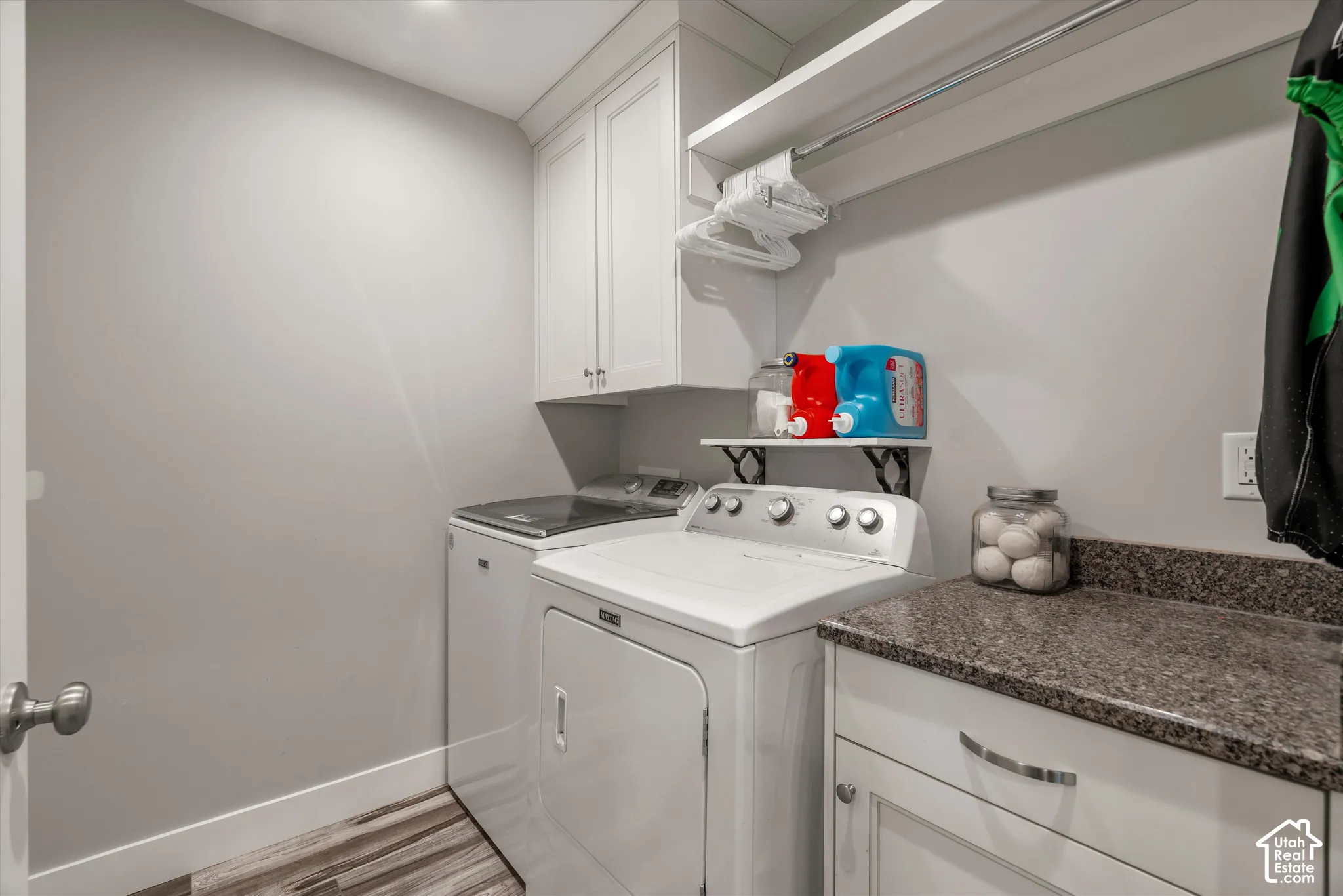 Laundry space with wood-finish flooring, white cabinetry, integrated sink, and granite-look countertop