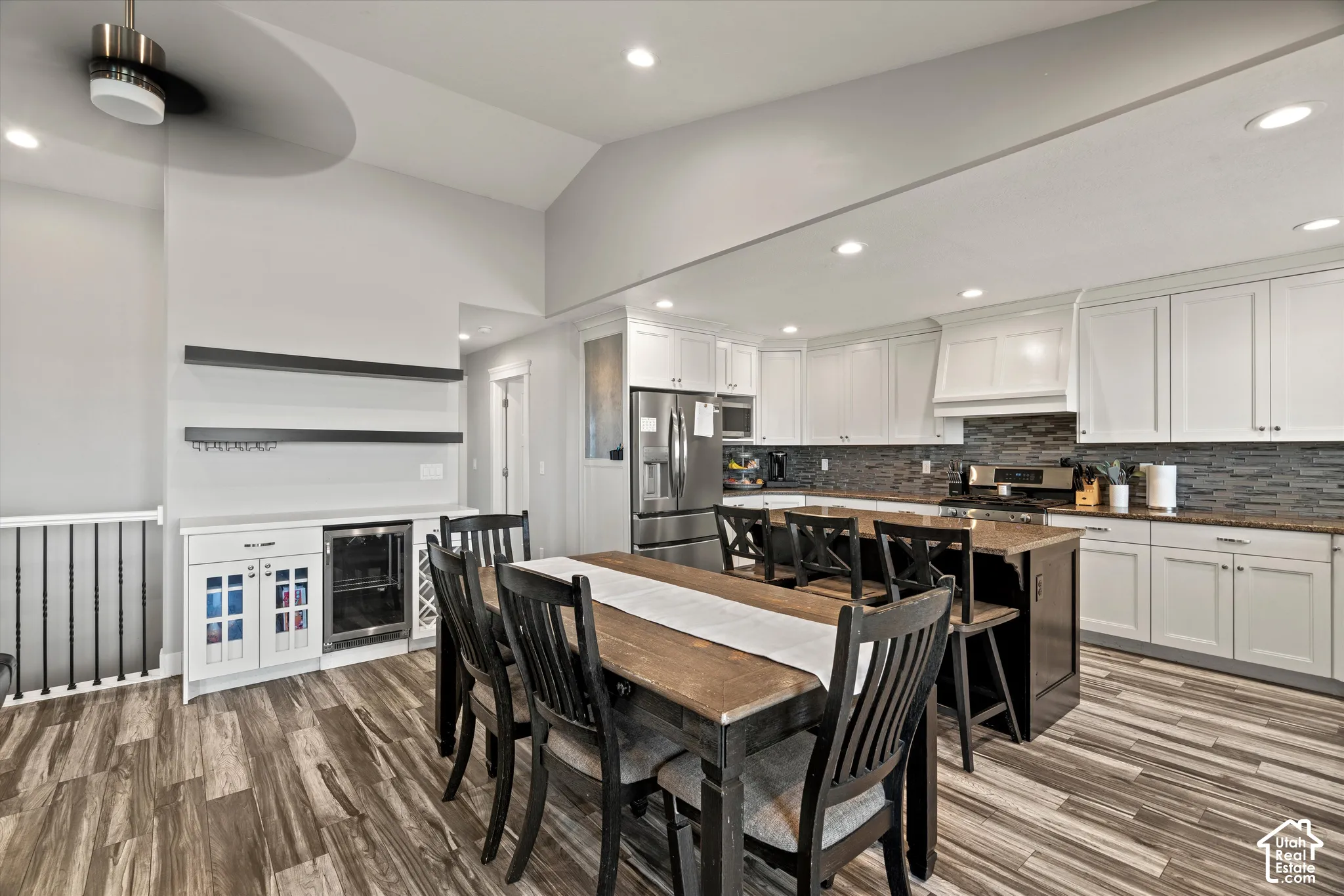 Spacious kitchen featuring white cabinetry, a dark tile backsplash, and wood-finish flooring
