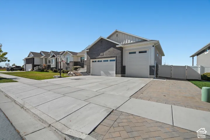 Exterior featuring brick and vertical siding accents, two attached garages, and a paved driveway