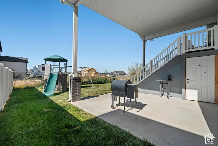 Covered patio with concrete flooring, supported by columns with brick accents and white railings