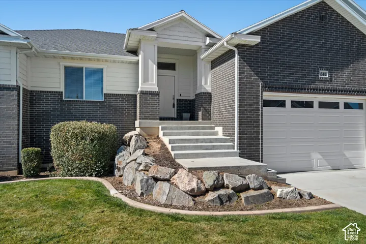 Exterior featuring dark brick and light-colored siding, a prominent front entry with an overhang, concrete steps, and a rock-landscaped bed