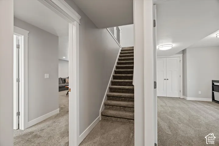 Carpeted staircase with white balusters, recessed lighting, and flat-panel doors
