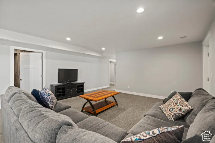 Recessed lighting illuminates the carpeted floor and light gray walls