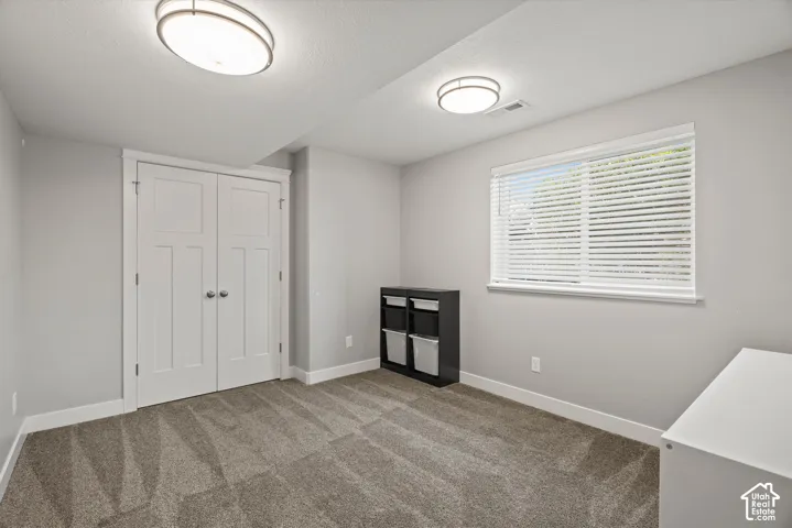 Neutral wall paint, plush carpeting, built-in dual-door closet, recessed window, and flush-mount lighting fixtures