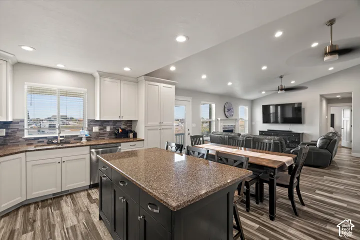Open-concept living area featuring a kitchen island, recessed lighting, wood-finish flooring, and a vaulted ceiling