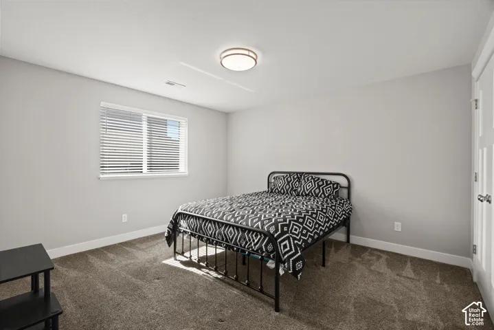 Plush carpet flooring, a large window with blinds, and a flush-mount ceiling light