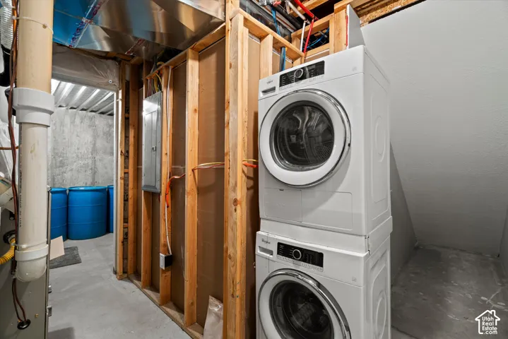 Washer and dryer unit, exposed wood framing, concrete flooring, and visible utility infrastructure