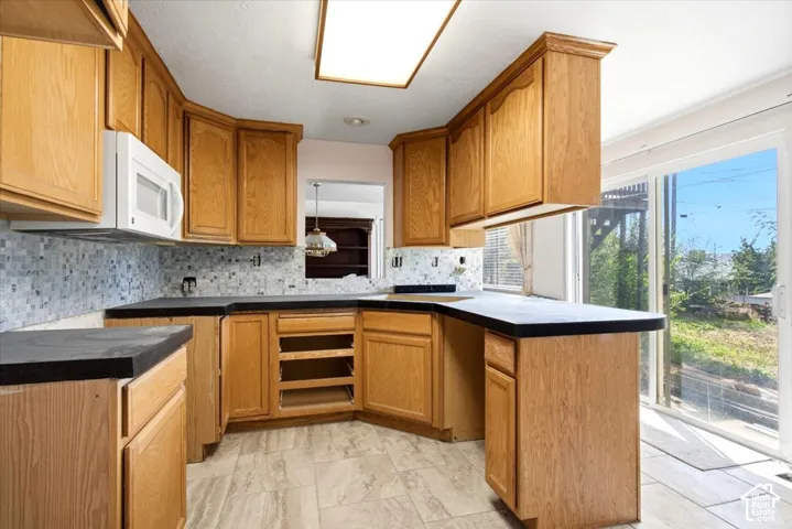 Wood-finish cabinetry with dark newly installed cement countertop, newly tiled backsplash, and plenty of cupboard space and natural lighting from 6 ft sliding glass doors.