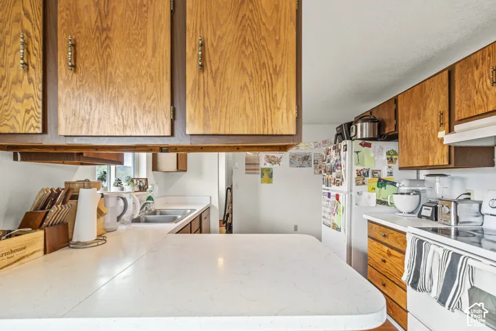 Wood-finish cabinetry with brass-tone hardware, white countertops, and a double basin sink