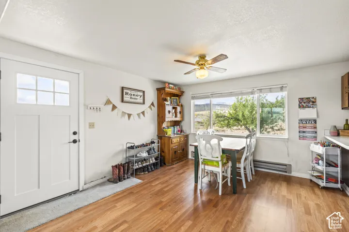 White paneled door with glass inserts, wood-finish flooring, ceiling fan with integrated lighting, large window with outdoor scenery, and built-in wood cabinetry