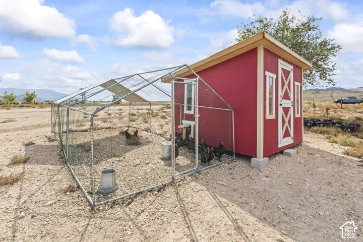 Red utility shed with white trim and X-brace door details, featuring an attached metal mesh enclosure