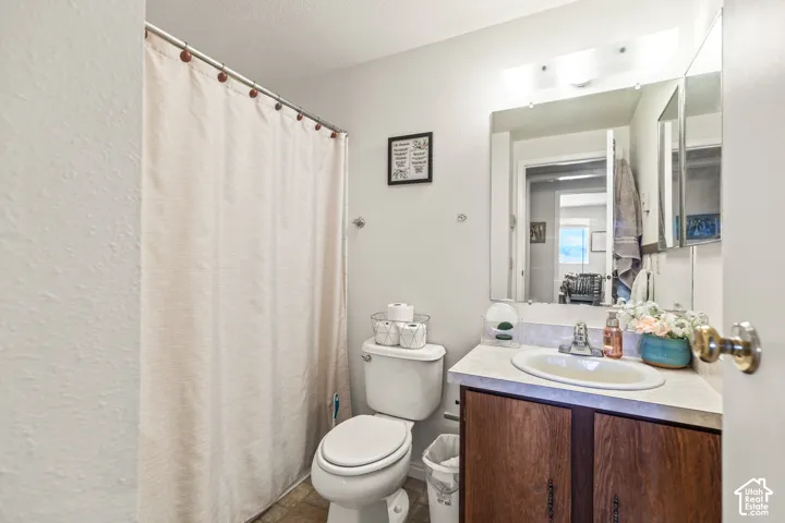 Bathroom featuring a vanity with a white countertop and wood-finish cabinetry, an oval sink, an overhead light fixture, and a wall-mounted medicine cabinet with a mirror