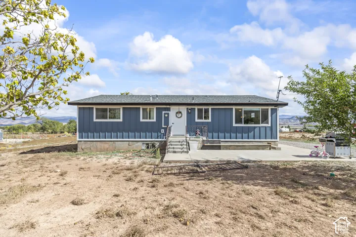 Blue exterior siding with white trim, dark roof, concrete front patio, and steps leading to the entrance