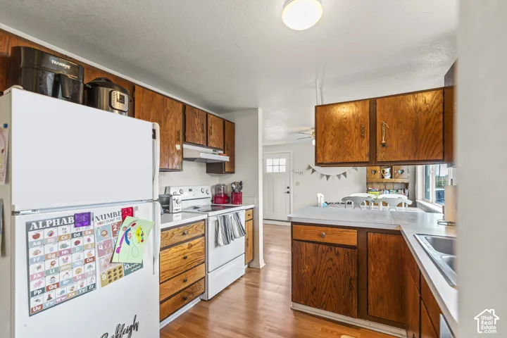 Wood-finish cabinetry, white countertops, built-in range, and a stainless steel sink