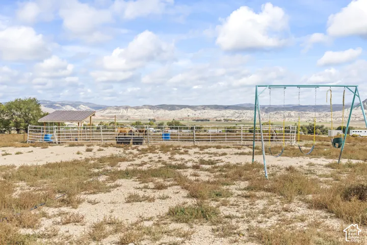 Metal-framed swing set, fenced animal enclosure with shelter, and distant mountain range
