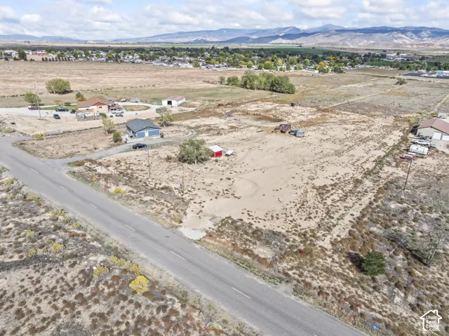 Expansive undeveloped lot with existing road access, distant mountain backdrop, and scattered shrubbery