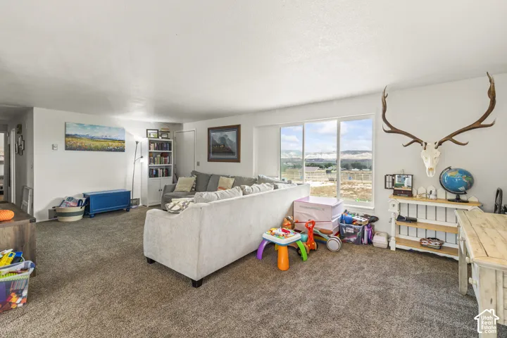Carpeted living area with white walls, built-in shelving, and large windows providing a distant landscape