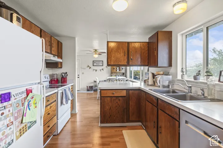 Kitchen featuring wood-finish cabinetry, white countertops, a stainless steel double-basin sink, and a built-in dishwasher
