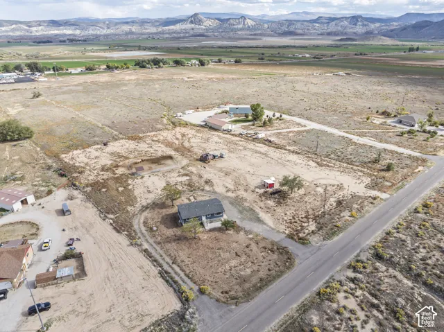 Expansive land parcel featuring a residential structure and partial paved road frontage