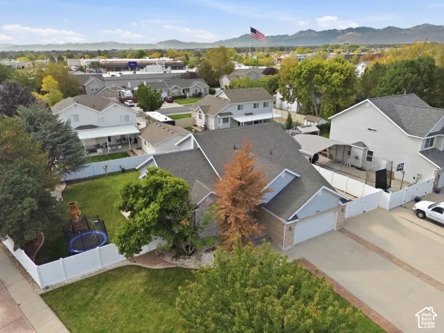 Expansive property featuring a multi-car driveway, attached garage, private fenced backyard with a green lawn, and mature landscaping