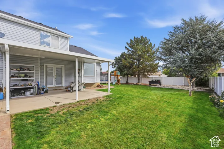 Expansive backyard with a covered patio, manicured lawn, and mature trees
