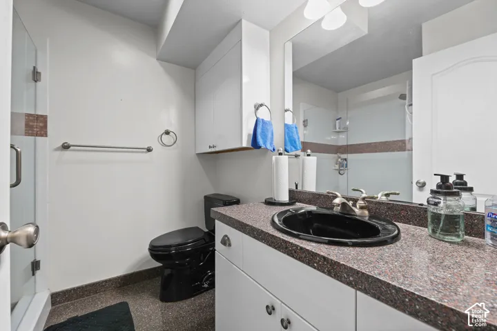 Vanity with brown speckled countertop, black undermount sink, and wall-mounted mirror