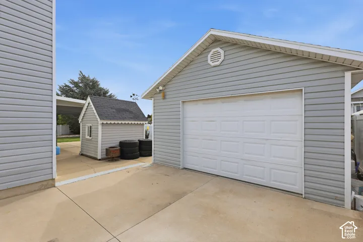 Attached two-car garage with a paneled door, gray siding, and an octagonal vent