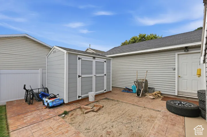 Outdoor shed with double doors, stamped concrete patio, and privacy fencing