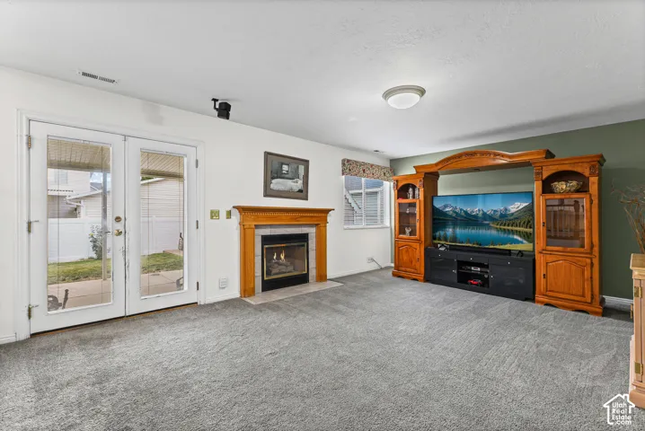 Carpeted living area with a fireplace featuring a wood mantel