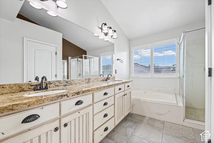 Dual vanity with stone countertop, integrated sinks, white cabinetry, and dark bronze fixtures