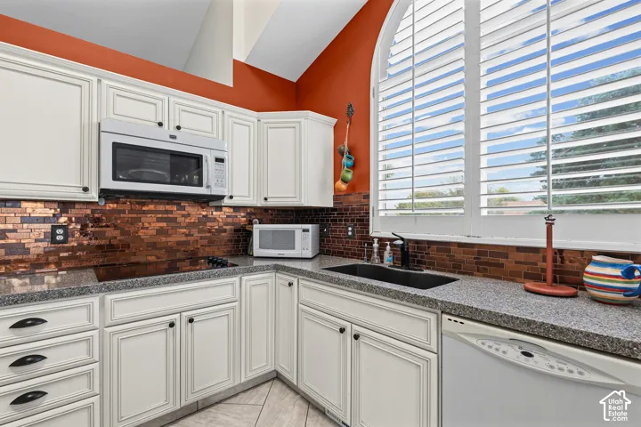 White cabinetry, stone-finish countertops, and a tiled backsplash