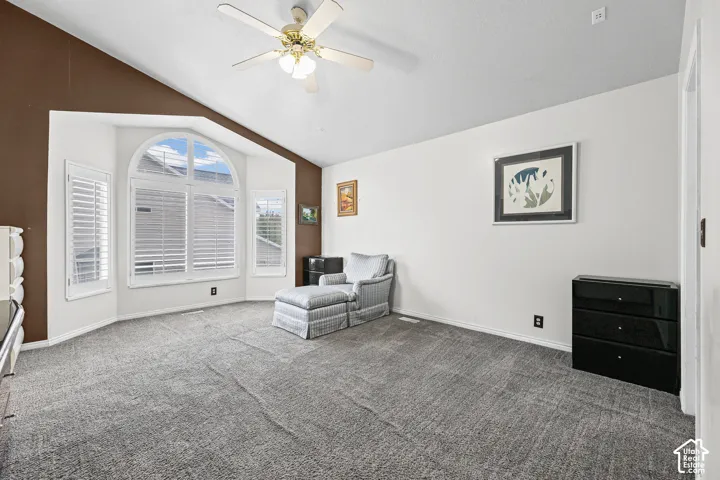 Vaulted ceilings with a ceiling fan, bay window featuring an arched transom, and plantation shutters