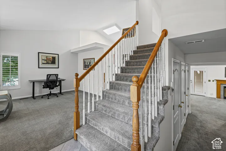 Carpeted staircase with wood handrails and white balusters