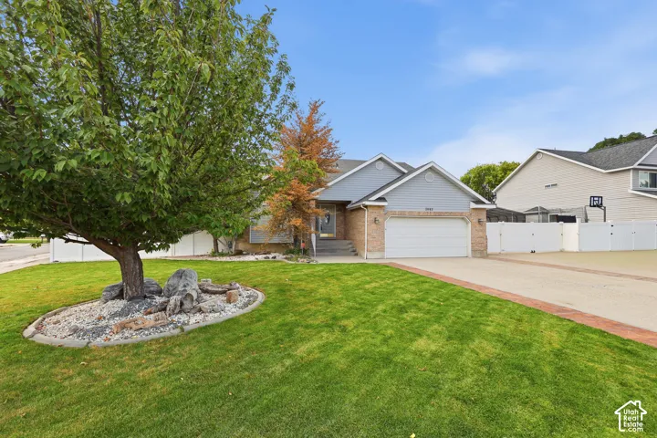 Brick and siding exterior with an attached garage, paved driveway, and manicured front lawn