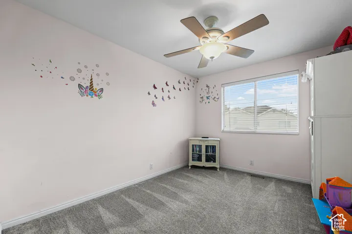 Ceiling fan with integrated lighting, window with horizontal blinds, and gray carpet flooring
